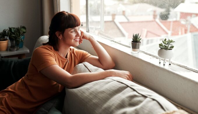 Woman sitting beside a bright window during recovery after a histamine flare, representing rest, symptom improvement, and gradual healing.