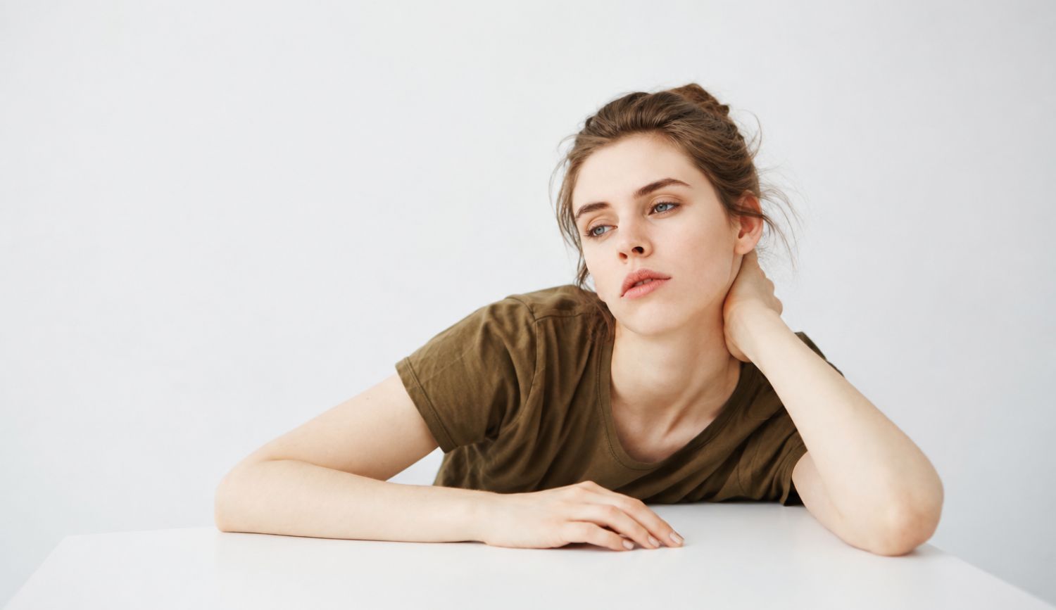 Woman looking exhausted at a white table, representing chronic fatigue syndrome and histamine intolerance overlap with deep fatigue and brain fog.